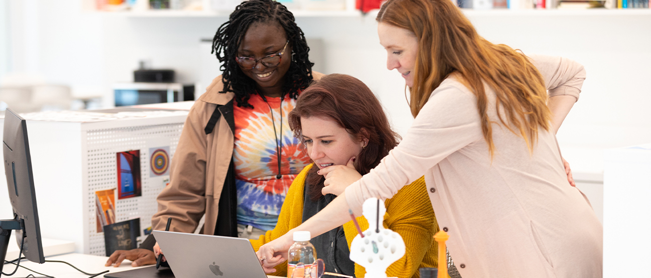 Graduate program web header with two students and a faculty member looking at a computer